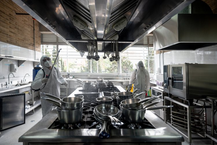 Workers sanitizing commercial kitchen with spray equipment in Atlanta, GA