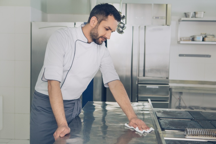 Person wiping stainless steel counter in commercial kitchen in Atlanta, GA